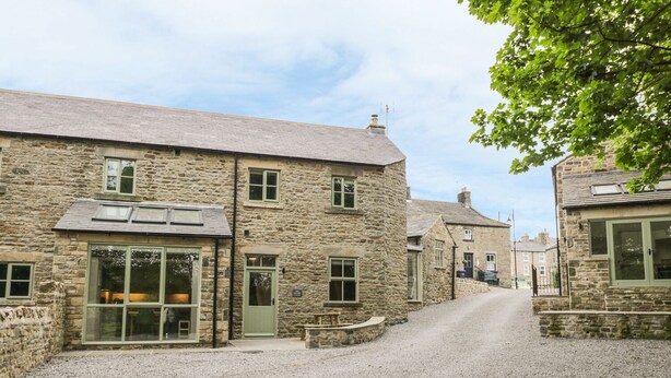 A stone building with a gravel driveway, a green door, and a window with a view. - Oak Cottage (Barnard Castle)
