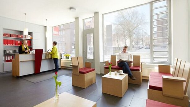 A reception area with a counter, seating, and large windows. - Hotel an der Marienkirche (Lübeck)