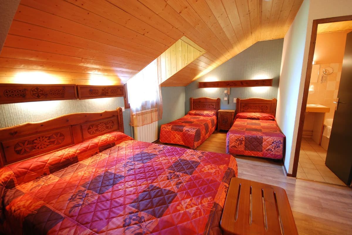 Un dormitorio con dos camas, cabeceros de madera y techo inclinado.