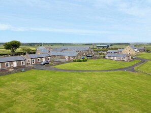 A rural property with multiple stone buildings, a large lawn, and a barn.