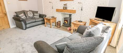 A cozy living room with a fireplace, a sofa, a television, and a painting on the wall.