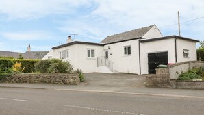 A two-story house with a garage, a front porch, and a stone wall. - Bedlinog (Amlwch)