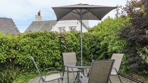 A patio with a table and four chairs, surrounded by gravel and greenery. - Bedlinog (Amlwch)