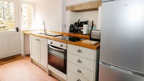 A modern kitchen with a built-in oven, a stainless steel refrigerator, and a wooden countertop.