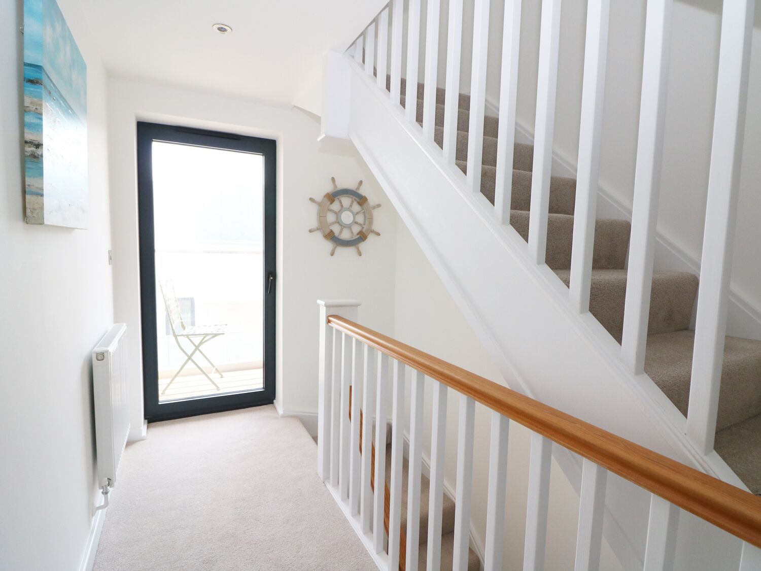 A staircase with white railings and a wooden handrail leading to a landing.