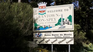 Welkomstbord voor Grantown-on-Spey, met een familiewapen, een brug en een kerk.