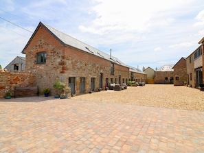 Un bâtiment en pierre avec une cour en gravier et des sièges à l'extérieur.