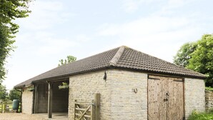 A stone building with a tiled roof, a wooden door, and a gravel driveway. - The Old Goat Barn at Trout Cottage (Somerton)