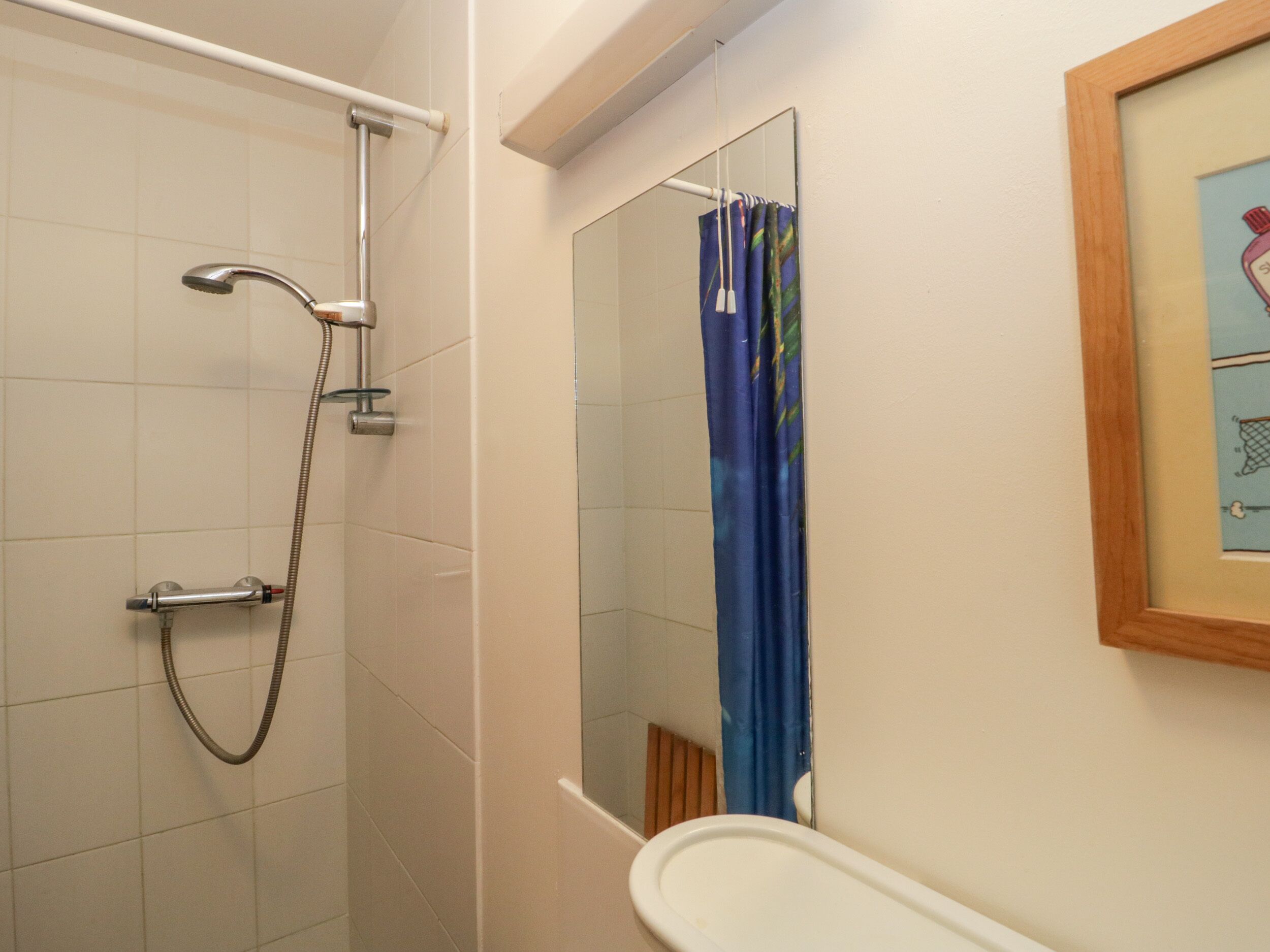 Un baño con ducha, lavamanos y espejo.