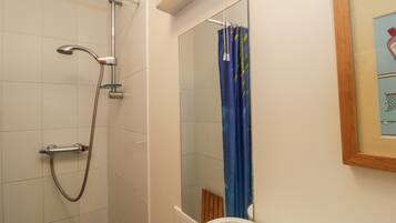 Un baño con ducha, lavamanos y espejo.