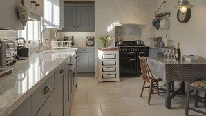 A kitchen with a central island, a dining table, and a stove. - 1 Florence Place (Falmouth)
