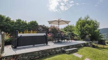 Um pátio com hidromassagem, móveis de exterior e um muro de pedra.