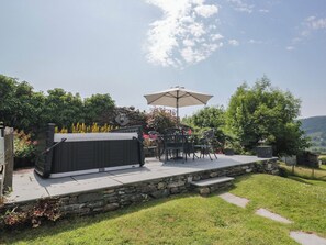 A patio with a hot tub, outdoor furniture, and a stone wall. - Rose Cottage (Broughton in Furness)