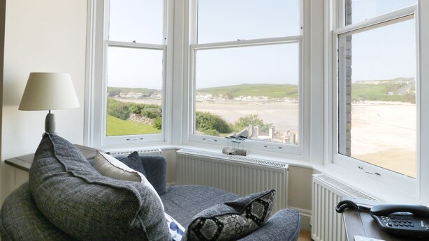 Une pièce avec vue sur un paysage côtier, grâce à de grandes fenêtres, et comprenant un radiateur, une lampe et un téléphone.