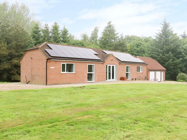 A two-story brick house with solar panels on the roof, a front door, and a garage. - Heron Lodge (Spilsby)