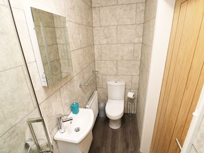 A small bathroom with a toilet, sink, and mirror. - Heron Lodge (Spilsby)