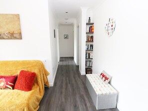 A narrow hallway with a bed on the left and a bookshelf on the right. - Heron Lodge (Spilsby)