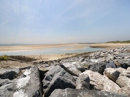 A rocky shoreline with a sandy beach and calm water.