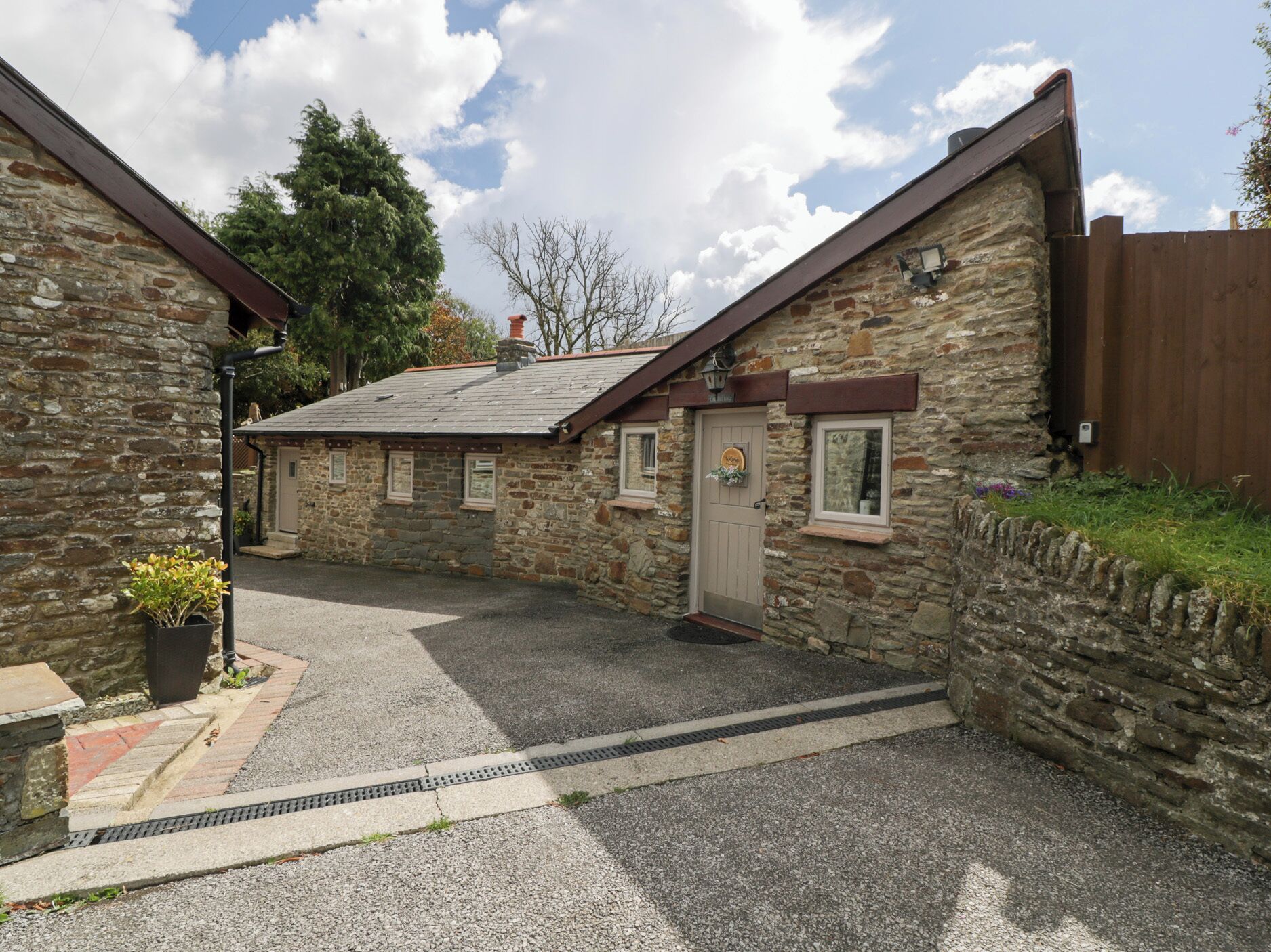 Un bâtiment en pierre avec un toit en pente, une porte en bois et une petite fenêtre.