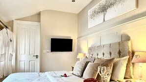 A hotel room with a bed, a bedside table with a red bowl of strawberries, a wine glass, and a lamp. - Caner Bach Lodge (Bridgend)