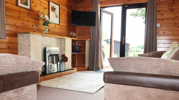 Un intérieur de chalet chaleureux avec des murs en bois, une cheminée, un téléviseur à écran plat et un coin salon confortable.