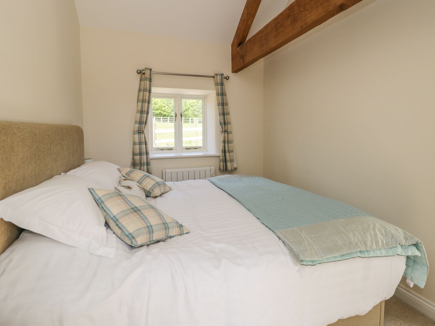 A bedroom with a bed, a window with curtains, and a radiator.