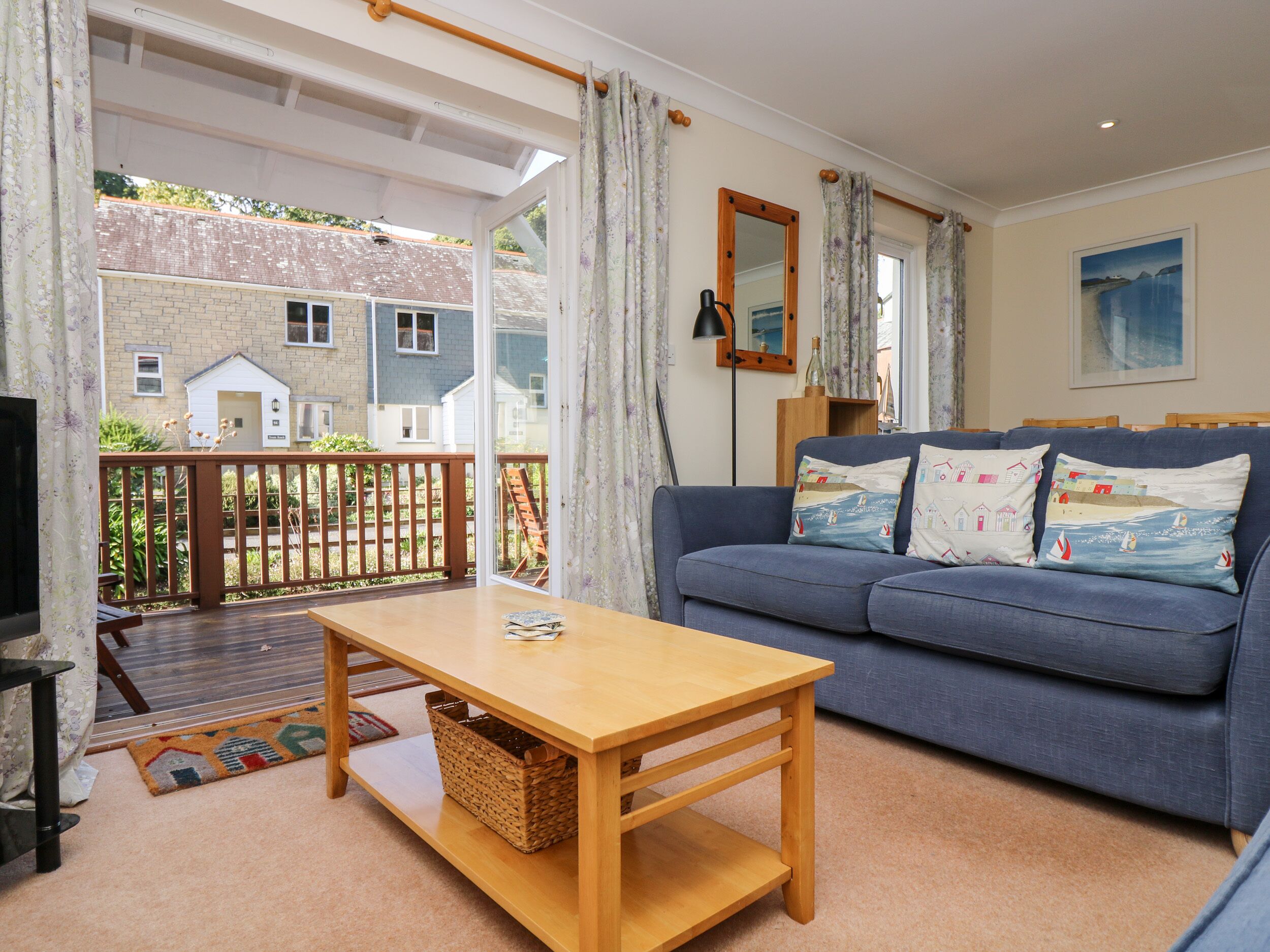 A cozy living room with a sofa, a wooden table, and a view of a house through a glass door.