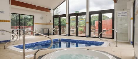 Una piscina con hidromasaje, barandillas de metal y un letrero que indica una profundidad de 1,4 metros.