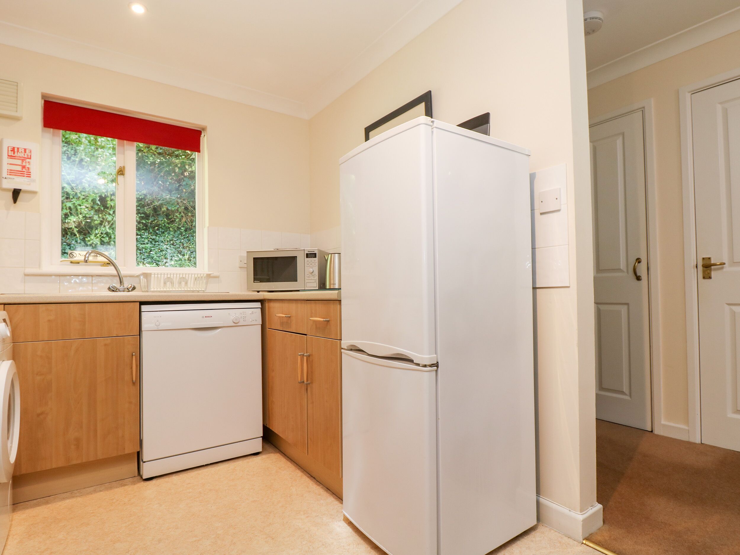 A compact kitchen with a dishwasher, microwave, and refrigerator.