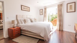A bedroom with a bed, bedside table, and a view of the outdoors. - Chy Lagen Hos (Newquay)