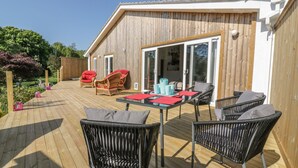 A wooden deck with outdoor furniture, including chairs and a table, and a sliding glass door leading to an interior space. - Chy Lagen Hos (Newquay)