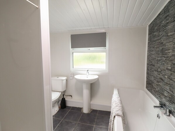 A bathroom with a toilet, sink, and bathtub. - Gwenallt (Bodorgan)
