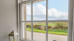 A window with a view of a rural landscape, a lantern, and binoculars on a windowsill. - Seaview-barsloisnach Cottage (Lochgilphead)