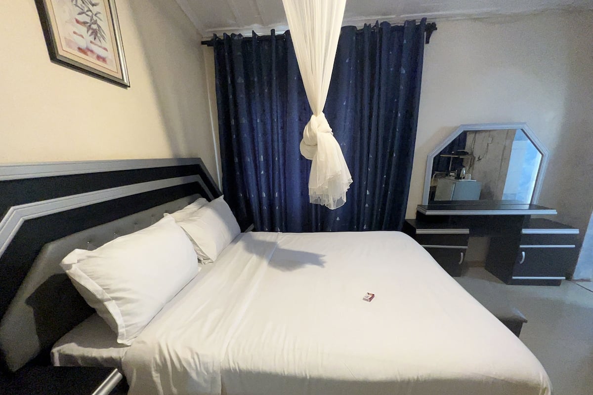 A hotel room with a bed, a desk, and a mirror.
