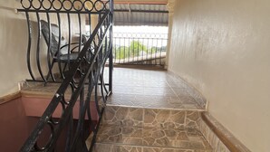 A staircase with stone tiles and a metal railing, leading to a balcony with a view of greenery. - Nalikwanda Guest House (Kabwe)