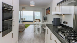 A modern kitchen with a gas stove, built-in oven, and a dining area with a view of the ocean.