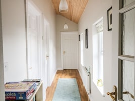 Un pasillo con puertas blancas, techo de madera y alfombra azul.