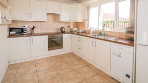 A modern kitchen with white cabinets, a built-in oven, a microwave, and a dishwasher. - Coneyville (Londonderry)