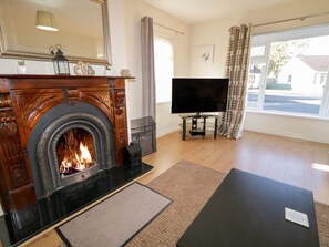 A living room with a fireplace, a television, and a large window with curtains. - Coneyville (Londonderry)
