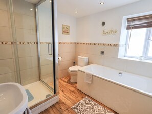 Un baño moderno con cabina de ducha de vidrio, bañera y retrete.