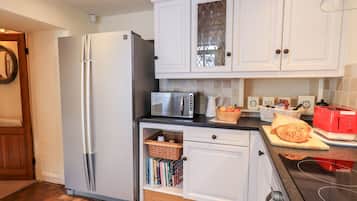 A modern kitchen with white cabinets, a stainless steel refrigerator, a microwave, and a red toaster.