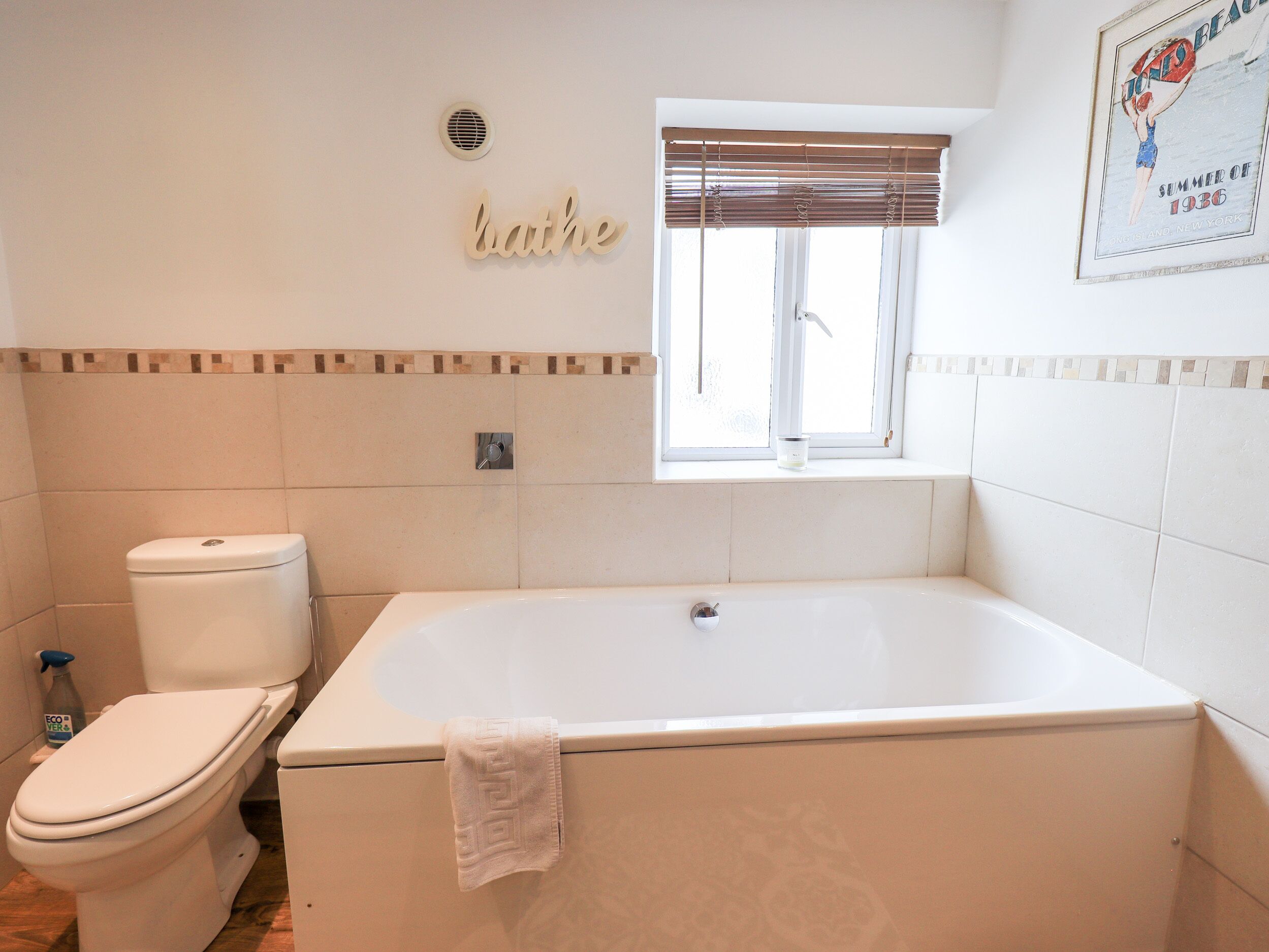 A bathroom with a toilet, bathtub, and a window.