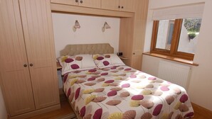 A bedroom with a bed, wooden wardrobe, and a window with a view. - The Milking Parlour (Wells)