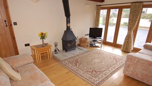 A cozy living room with a fireplace, sofas, a television, and a large window. - The Milking Parlour (Wells)