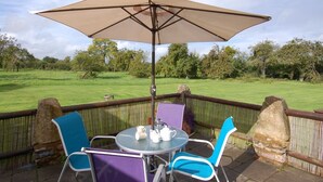 An outdoor patio with a round table, two chairs, and a large umbrella. - The Milking Parlour (Wells)