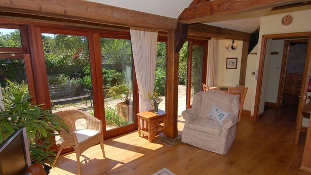 A spacious living room with wooden floors, a large window, and a comfortable chair.