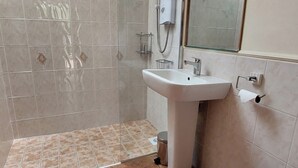 A bathroom with a white sink, a mirror, and a shower area.