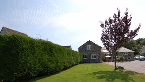 A stone building with a well-maintained lawn and a hedge. - Jacobs Barn (Lifton)
