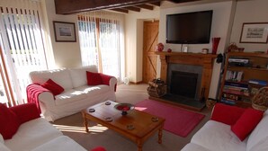 A living room with a white sofa, red cushions, a wooden coffee table, a fireplace, and a bookshelf. - Jacobs Barn (Lifton)