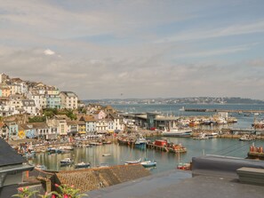 A coastal town with colorful buildings, a marina with boats, and a lighthouse in the distance. - Harbour View Retreat (Brixham)